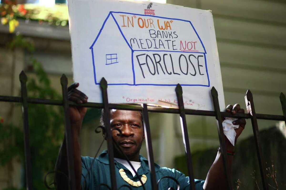 Luster Mitchell, Jr. holds a sign during a rally to support his mom, Dixie Mitchell, 71, on Tuesday, October 18, 2011. Mitchell's home of 44 years is scheduled to go to auction on October 28th after years of battling with Ocwen Financial.