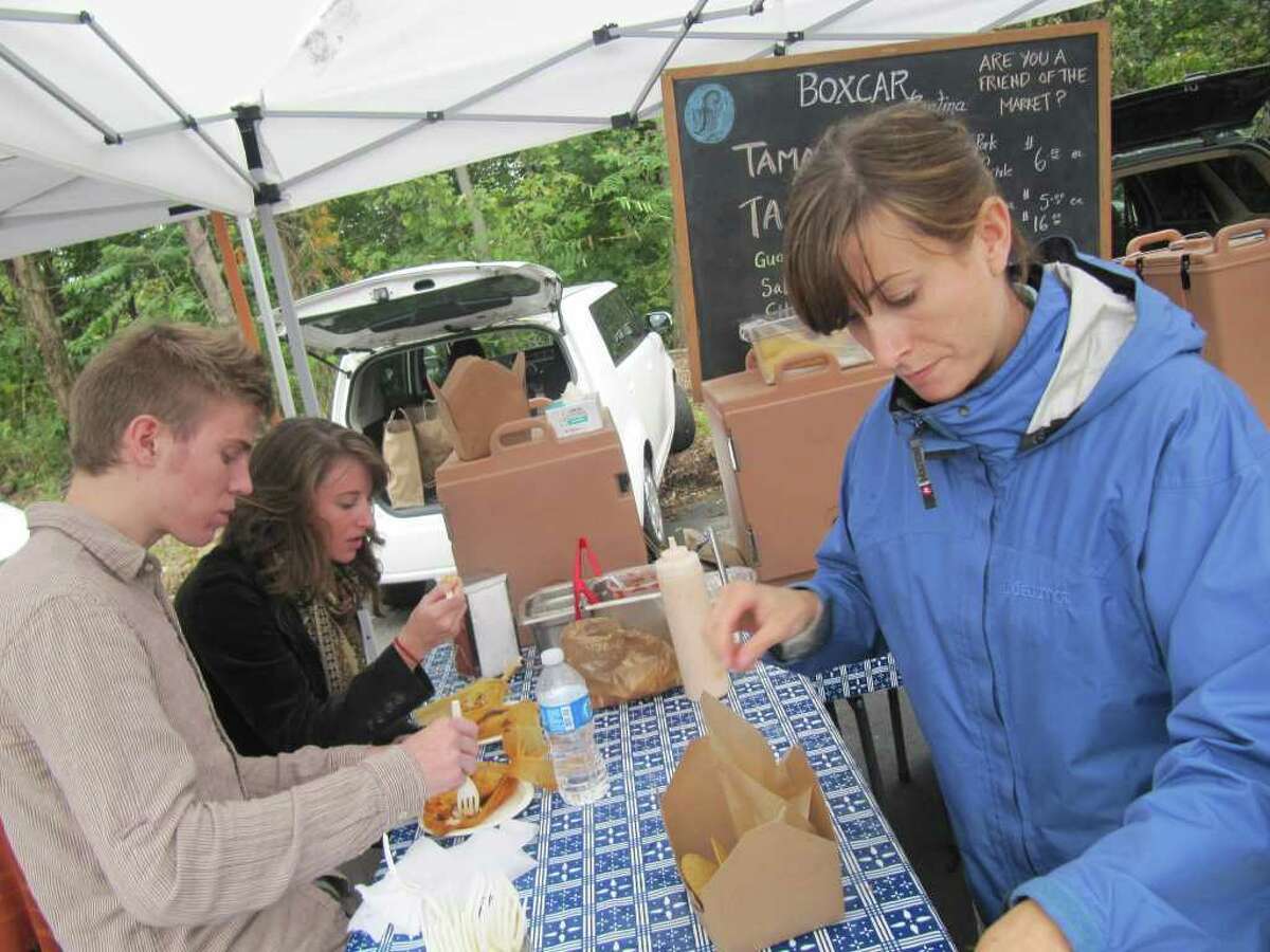 Amy Clark and Ben Kuyper, at left, were among the faithful that visited the Westport Farmers' Market on Thursday, despite the fact it rained. In this photo, Clark and Kuyper are enjoying tamales made by Greenwich-based Boxcar Cantina. At right is Kelly Walsh, Boxcar Cantina's marketing manager.