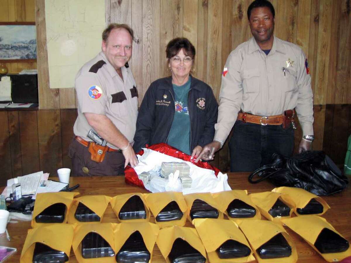 This December 2006 evidentiary photo provided by R. Christopher Goldsmith, lawyer for Gregory Fuller, shows, from left, Shelby County, Texas, Precinct Four Constable Randy Whatley, Shelby County District Attorney Lynda Kaye Russell and Tenaha Deputy City Marshal Barry Washington, posing with $81,000 cash and 15 kilos of cocaine. Fuller got probation for aggravated cocaine possession, a first degree felony that would normally result in a long prison sentence, after he agreed to forfeit the cash. Russell's system of allowing suspected drug runners and money launderers to receive extremely light sentences, or even escape criminal charges altogether, if they forfeited their cash to the prosecutor?s office is being investigated by the federal government. (AP Photo/R. Christopher Goldsmith)