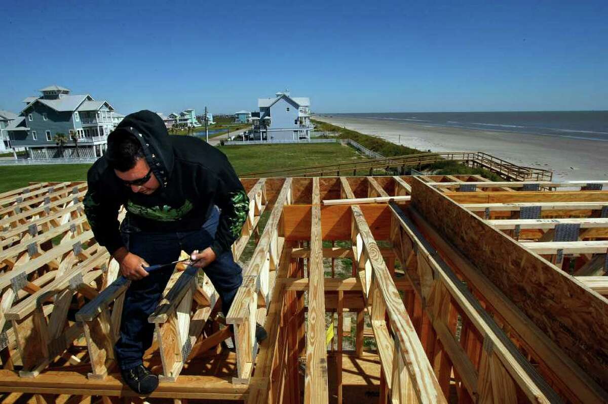 JOHNNY HANSON : CHRONICLE OPEN TO GULF: Juan Pena works Wednesday on a new home in the Beachside Village neighborhood on Galveston's West End, about a mile from the city's seawall. Scientists at Rice University question whether anyone should live on that end of the island, a topic of growing debate.