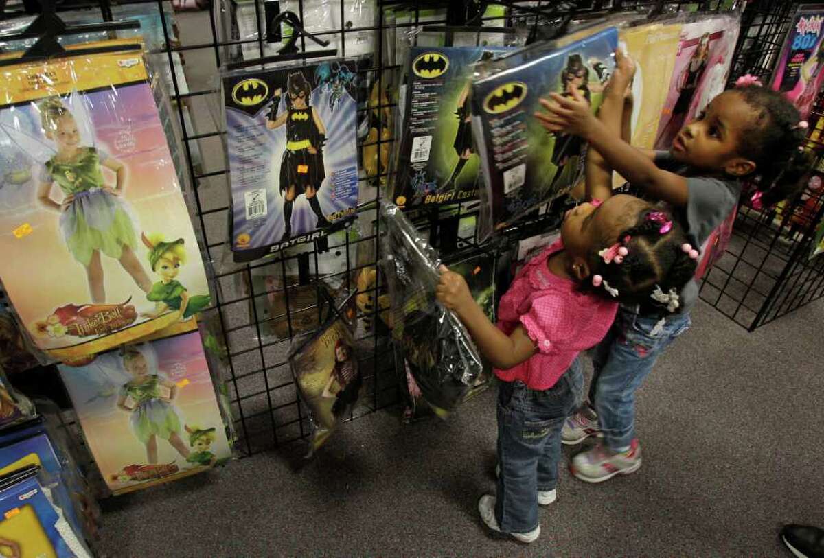 Melissa Phillip Photos : Chronicle FOR THE YOUNG: Jaida Bailey, 2, left, and her sister Journey Bailey, 3, of Rosenberg, look at Batgirl costumes at a Halloween Express store on the Southwest Freeway in Sugar Land. Halloween Express has six pop-up stores in the area.