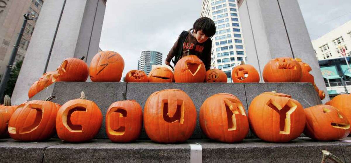 Rick Navarro, 6, looks over carved pumpkins, some spelling out "Occupy," after clambering atop a platform at the Occupy Seattle site Monday, Oct. 31, 2011, in downtown Seattle. Protesters moved their encampment over the weekend to the campus of Seattle Central Community College, but some continue to demonstrate at the downtown location during the day.