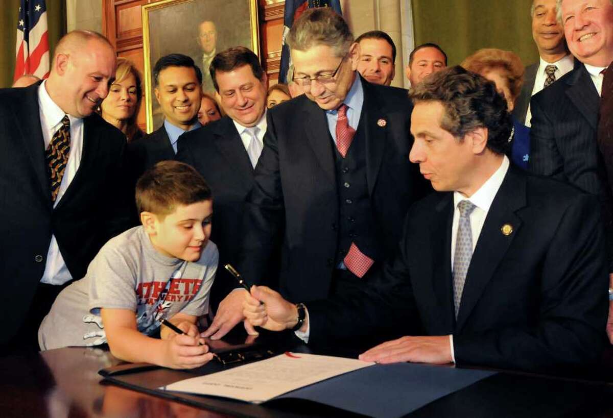 Gov. Andrew Cuomo, right, hands a pen to Alexander Smith, 10, of Clifton Park, who has autism, left, after signing a bill to allow autistic patients covered medical care on Tuesday, Nov. 1, 2011, at the Capitol in Albany, N.Y. (Cindy Schultz / Times Union)