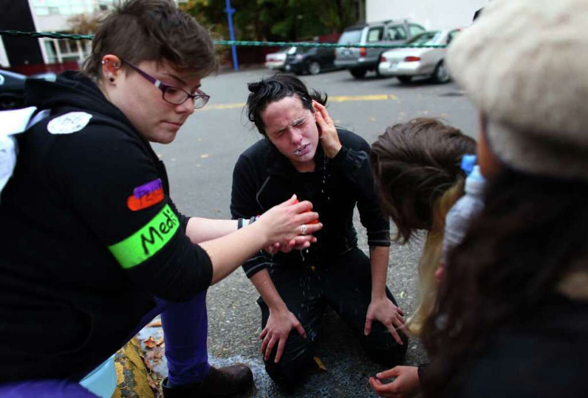 A woman is treated after being maced in the face during an Occupy Seattle protest outside a Chase Bank branch on Capitol Hill on Wednesday, Nov. 2, 2011.