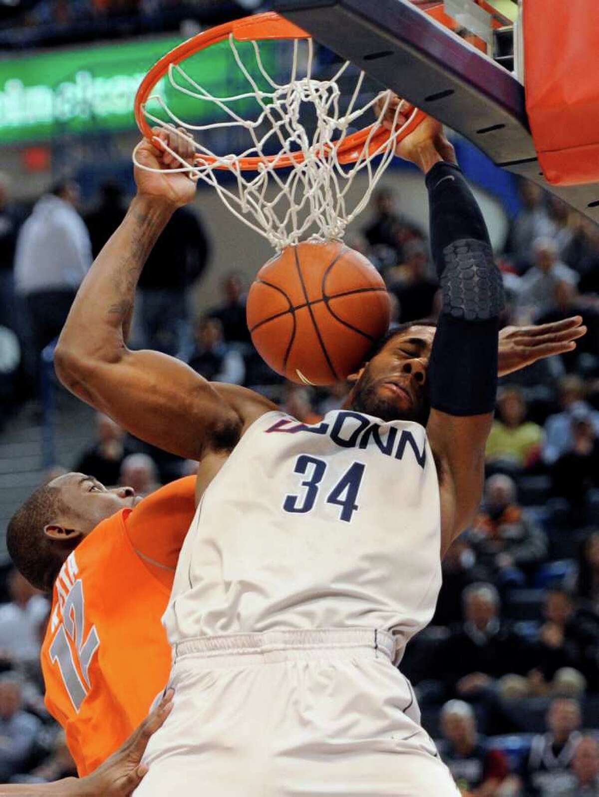 Connecticut's Alex Oriakhi dunks the ball while guarded by Syracuse's Baye Moussa Keita during the first half of an NCAA college basketball game in Hartford, Conn., Wednesday, Feb. 2, 2011. (AP Photo/Jessica Hill)