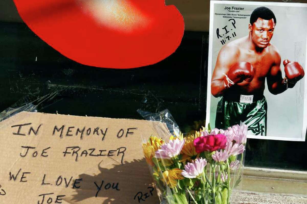 An old photograph and flowers have been placed at a makeshift memorial at the former location of Joe Frazier's gym, that is now a furniture outlet store, Tuesday, Nov. 8, 2011 in Philadelphia. Frazier died Monday night after a brief battle with liver cancer at 67. (AP Photo/Alex Brandon)
