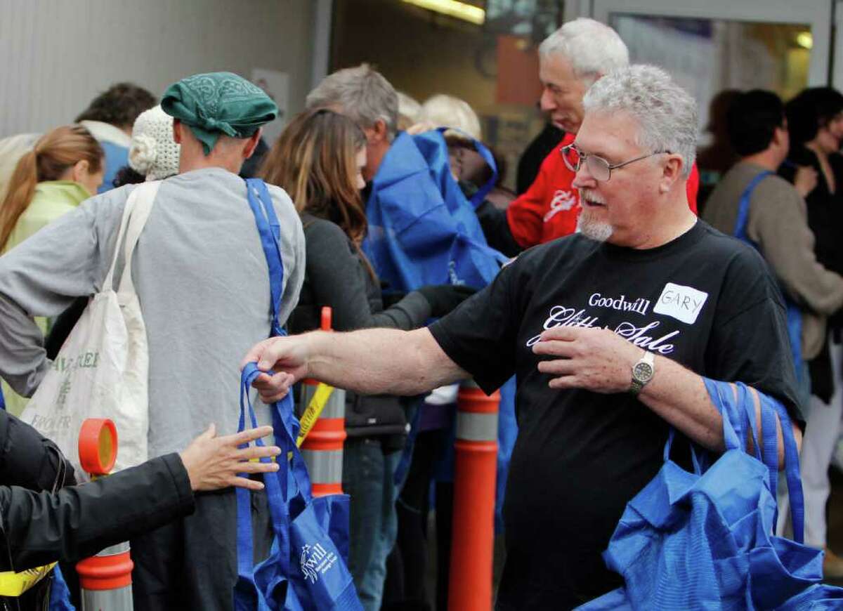 Goodwill employees pass out reuseable bags to shoppers moments before the opening of the Glitter Sale at the Seattle Goodwill's Dearborn Street store on Saturday Nov. 12, 2011. The Glitter Sale is an annual sale featuring glitzy and glamorous clothing, jewelry, and bags. All of the proceeds from the sale go to support Goodwill's free job training and educational programs.