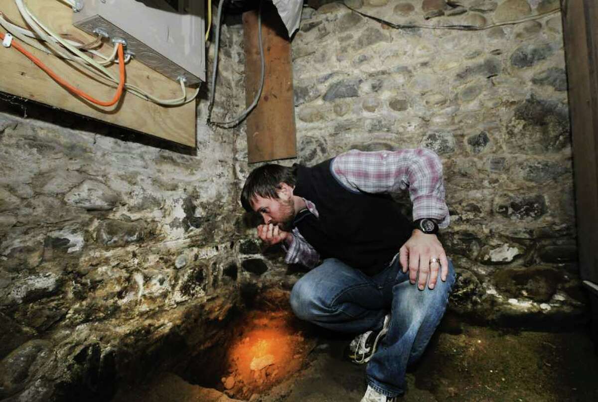 John Young sniffs some of the dirt from beneath the slab floor in the basement of his home in West Sand Lake, N.Y. Young found a distinct odor of heating oil in the dirt. (Skip Dickstein/Times Union)