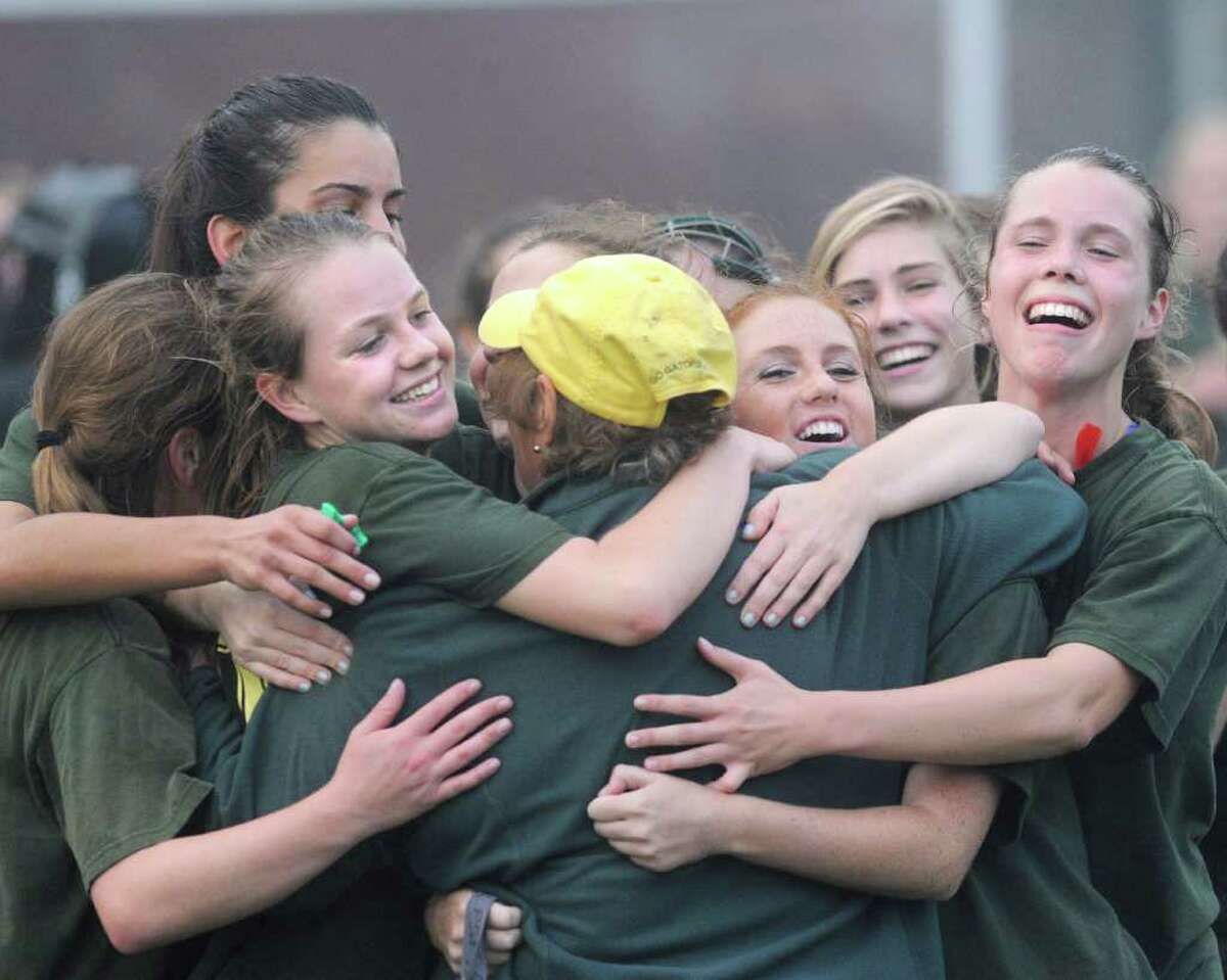 Convent of the Sacred Heart field hockey coach Angela Tammaro (wearing yellow hat back to camera) gets smothered in a sea of hugs from her players after Greenwich Academy defeated Convent of the Sacred Heart 2-1 in overtime to win the FAA field hockey championship at Greenwich Academy, Thursday afternoon, Nov. 10, 2011.