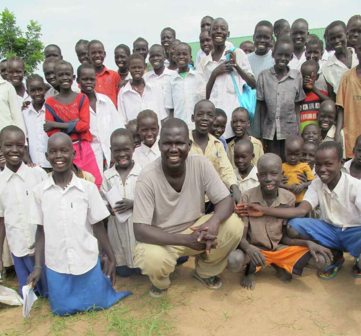 Gabriel Bol Deng, center, founder and director of the nonprofit foundation Hope for Ariang, spends time with some of the children who are benefiting from a new school that is being constructed in the village of Ariang, in Southern Sudan, Africa, through the fundraising efforts of his foundation. An art show that will raises funds for educational initiatives for the women of the village is set for Sunday, Nov. 27, at the Fairfield Arts Center in Fairfield. For more information, visit thesudancanvasproject.org.