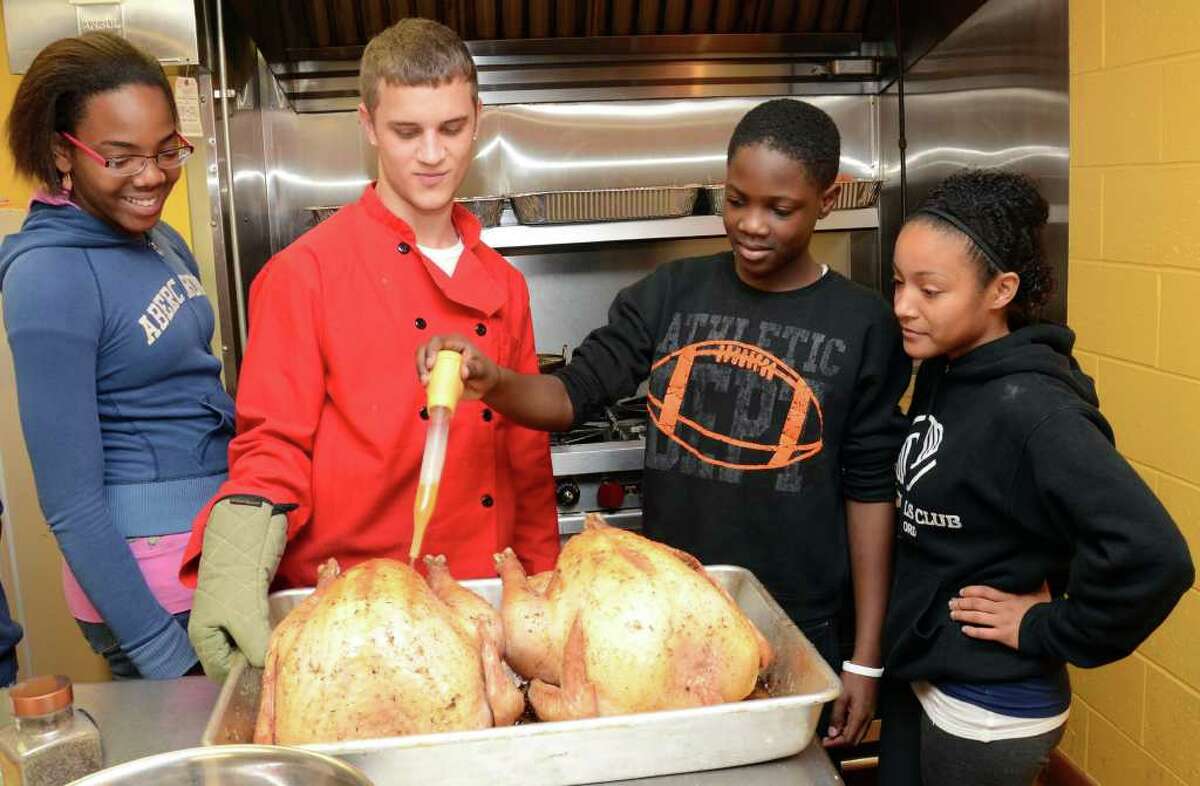 Boys & Girls Club member, Teddy Saint-Louis, 12, third from left, bastes the turkey at the Boys & Girls Club of Stamford for a Thanksgiving feast at the club on Wednesday, Nov. 23, 2011. Looking on from left Lonita Brown, 18; Jr. Chef Austin Drew, 20; and Boys & Girls Club staffer Jasmine Forbes, 19.