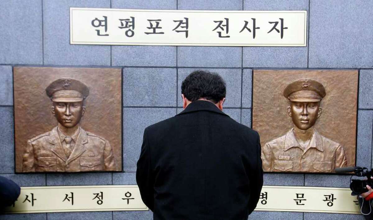 A man pays a silent tribute in front of two bust sculptures of two killed marines during a memorial service on Yeonpyeong Island, South Korea, Wednesday, Nov. 23, 2011. South Korea marked the first anniversary of North Korea's deadly artillery attack on the front-line island Wednesday.