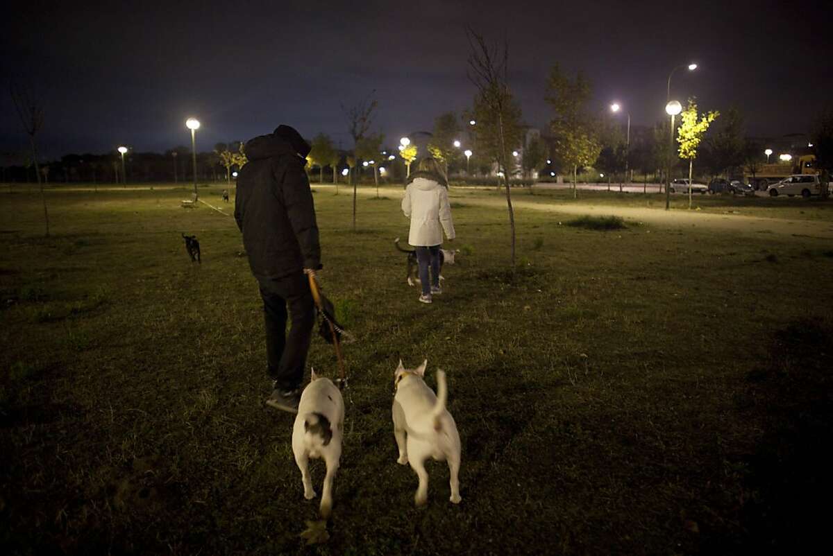 Azucena Paredes, an unemployed mother of three children, right, and her boyfriend Odin walk their dogs early in the morning before their eviction in Madrid, Friday, Nov. 18, 2011. As in many European countries, Spanish mortgages are not like US-style ones in which defaulters can return the keys to the bank and walk away from their debt, albeit with their credit rating in ruins. Here, mortgage holders not only have to give the house back, but also pay off bank debt. If they cannot, upon their death it is passed on to their relatives. (AP Photo/Arturo Rodriguez)