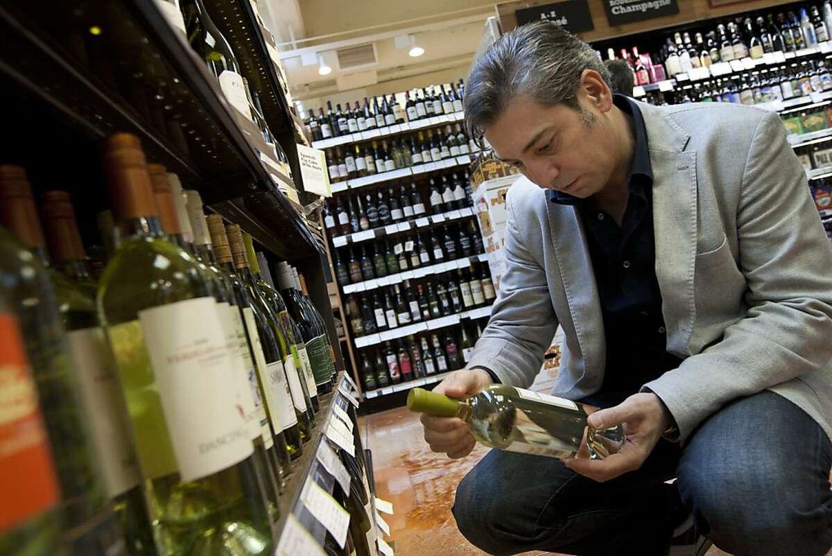 Nicolas Luisotti, San Francisco Opera director, looks for a bottle of white wine to cook with while he grocery shops with his wife, Rita Simonini, at the Whole Foods Market on Franklin Street in San Francisco, CA Thursday morning, October 20, 2011. Photo by Erin Lubin/Special to Chronicle