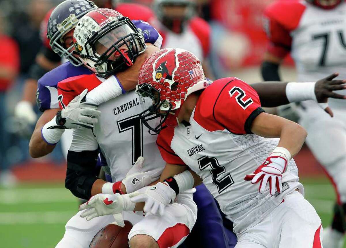 The Cardinal's Daniel Ramirez is shaken loose from the ball by Warrior defensive back Dalton Miller and drops the ball as Warren plays Harlingen in third round playoff action at Buccaneer Stadium in Corpus Christi on November 26, 2011. Tom Reel/Staff