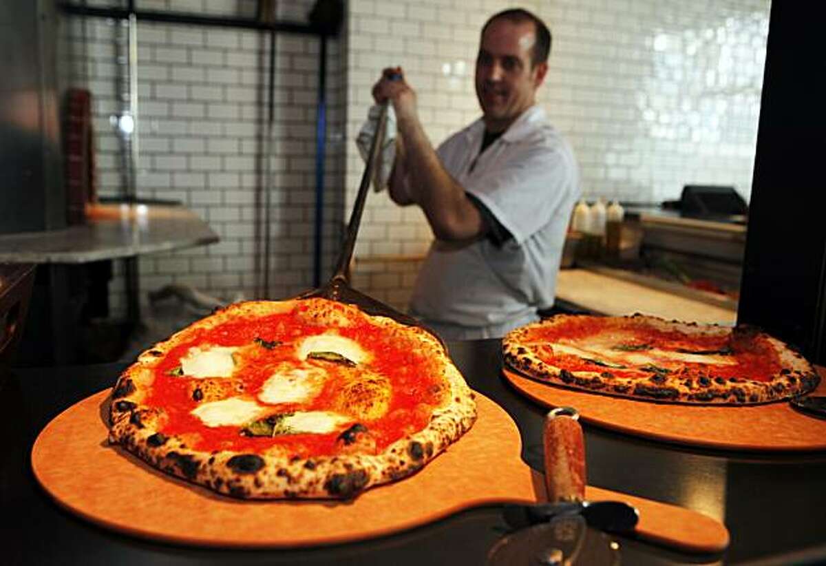 Zero Zero厨师克里斯·威利从烧柴砖烤箱中拿出一个用水牛马苏里拉奶酪制作的玛格丽特特级披萨。照片摄于2010年9月25日星期六。