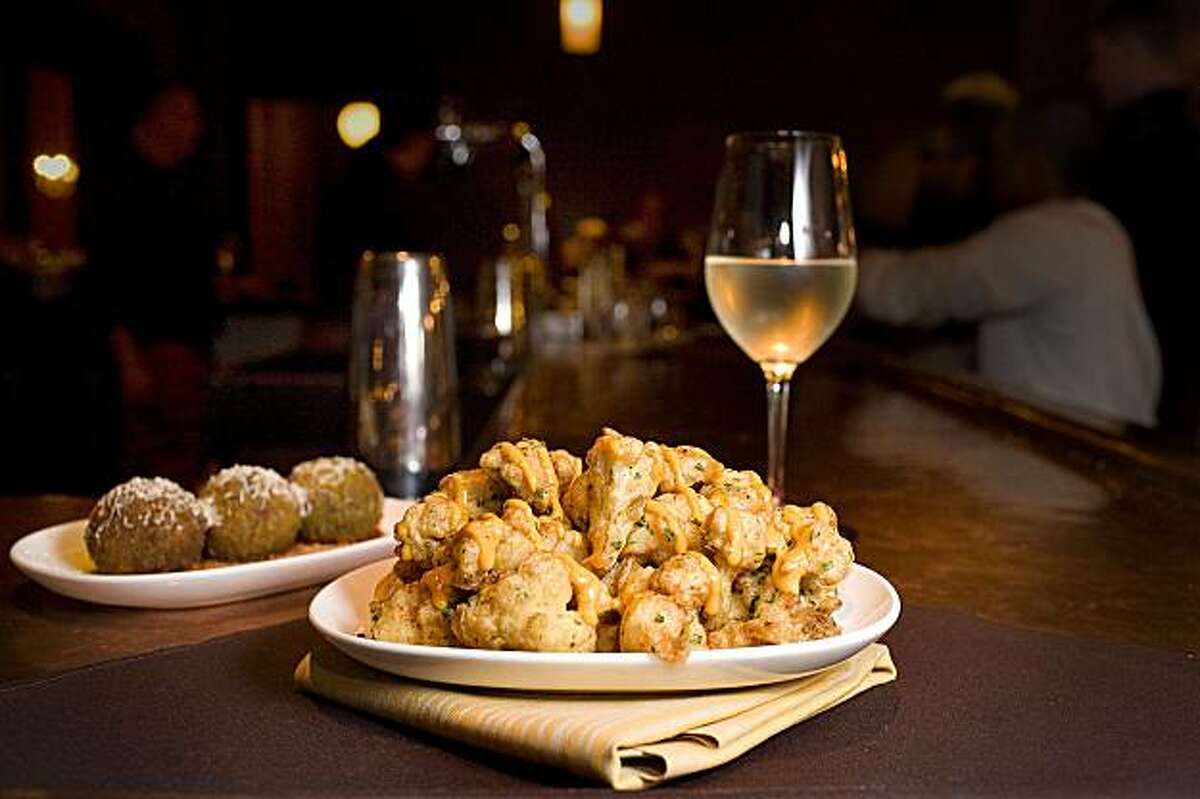 Calabrian chili and beer battered cauliflower florets with smokey paprika-saffron aioli, center, basil pesto arancini with molten burrata center, with a glass of a 2008 Duckhorn Napa Valley Sauvignon Blanc on the bar at Chef Michael Chiarello's restaurant, Bottega, in Yountville, on Thursday, Feb. 11, 2010.