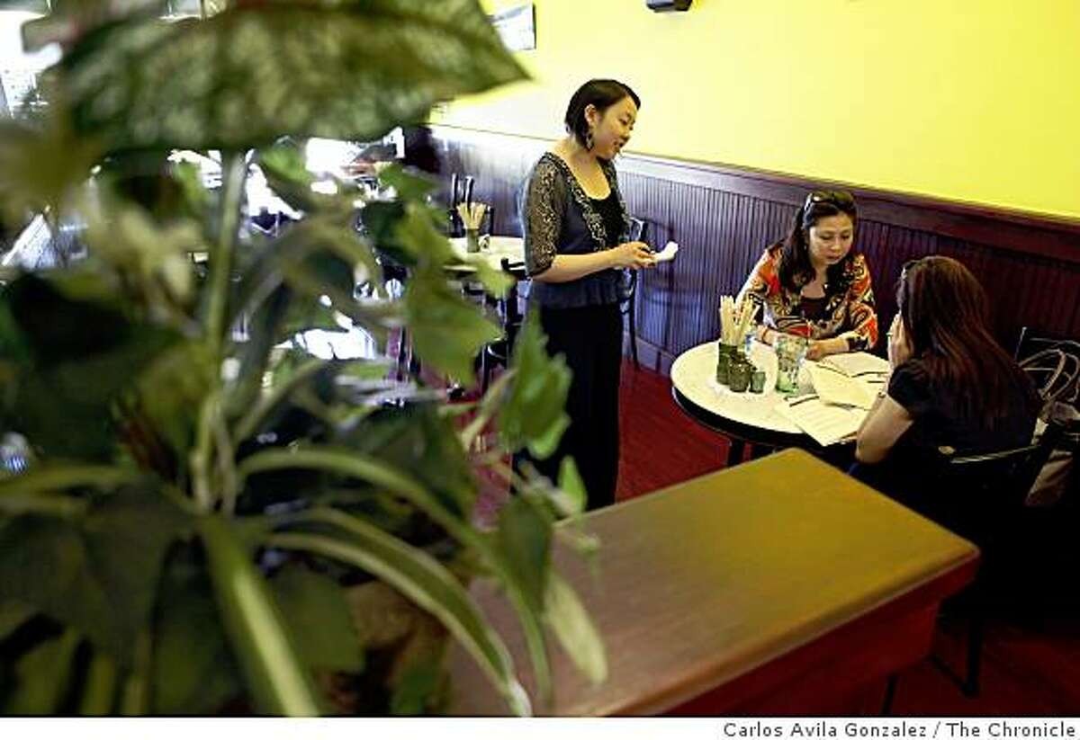 Yshel Lok, left, waits on sisters Tran and Tram Nguyen of El Cerrito, at Kopitiam, a Singaporean cafe in Lafayette, Calif., on Wednesday, April 22, 2009.