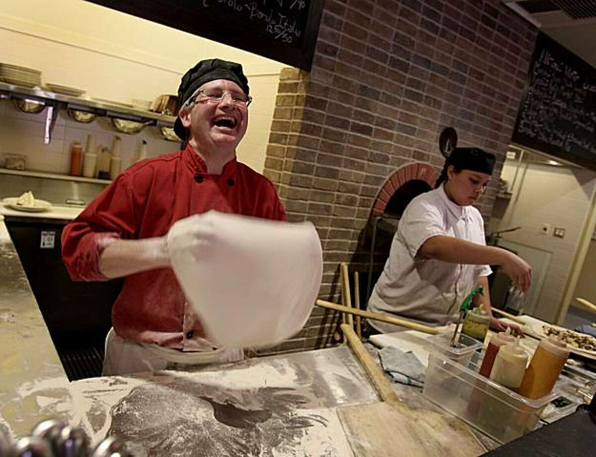 John Franchetti laughs as he prepares pizza dough for his wood burning oven. At right is former chef Marilyn Hurley. Rosso Pizzeria and Wine Bar is located at 53 Montgomery Drive in Santa Rosa. (Photo by Brant Ward/San Francisco Chronicle)