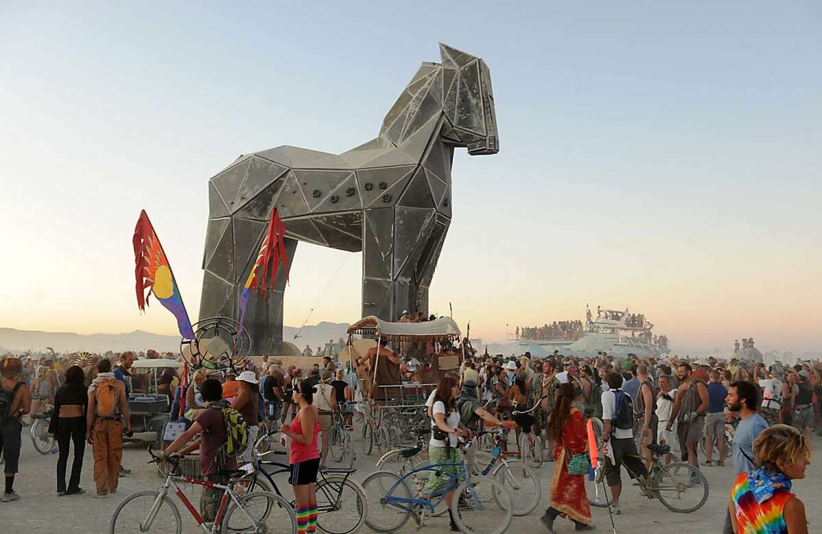 People gather around the Trojan Horse at it is pulled across the "playa" at the Burning Man festival in Gerlach, Nev. on Friday, Sept. 2, 2011. (AP Photo/Reno Gazette-Journal, Andy Barron)