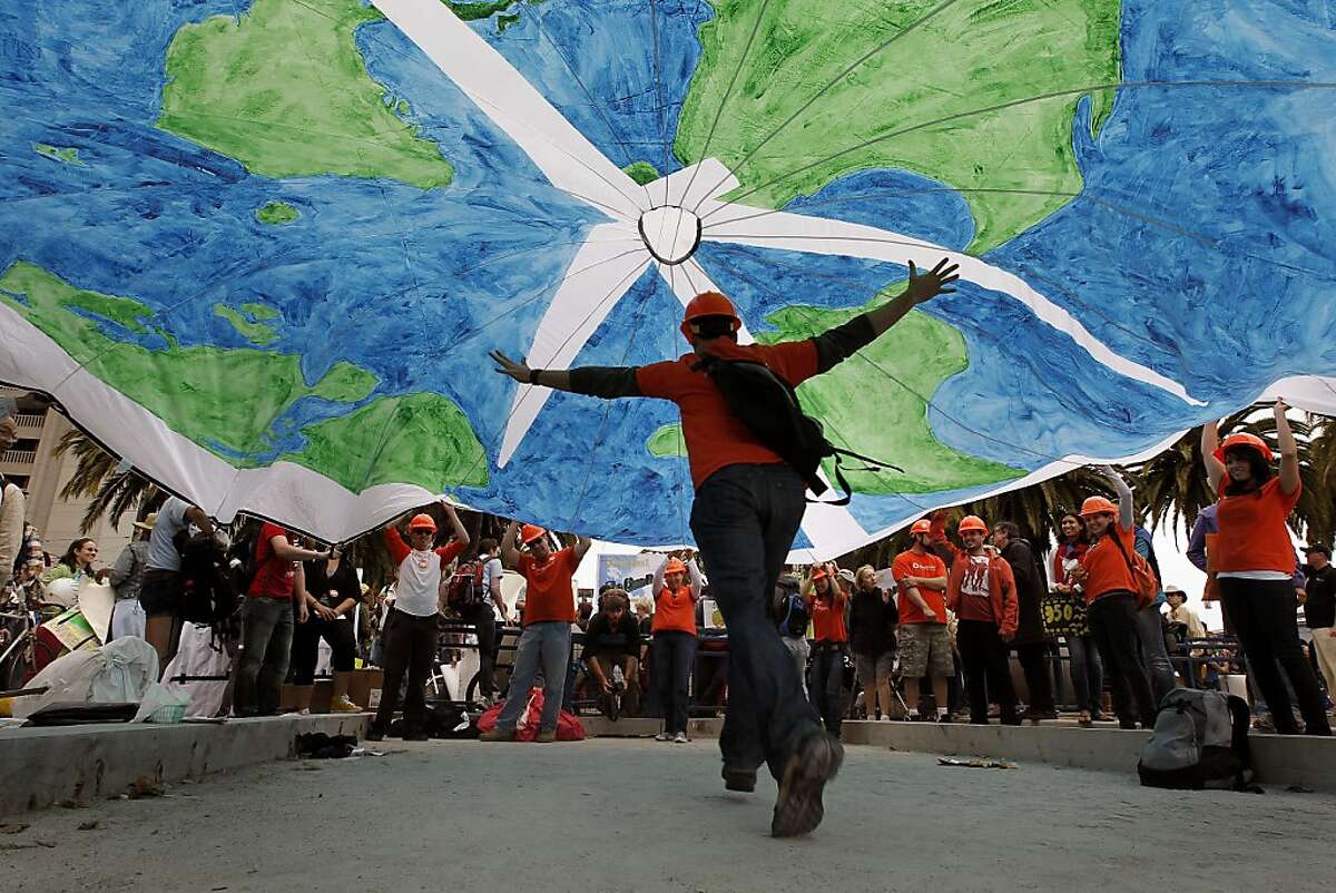 People with the solar company "Sungevity", take turns running under a parachute globe they brought along, as they joined hundreds for a parade and rally for "Moving Planet" demanding solutions to climate change, peace and sustainability, in San Francisco, Ca., on Saturday September 24, 2011.