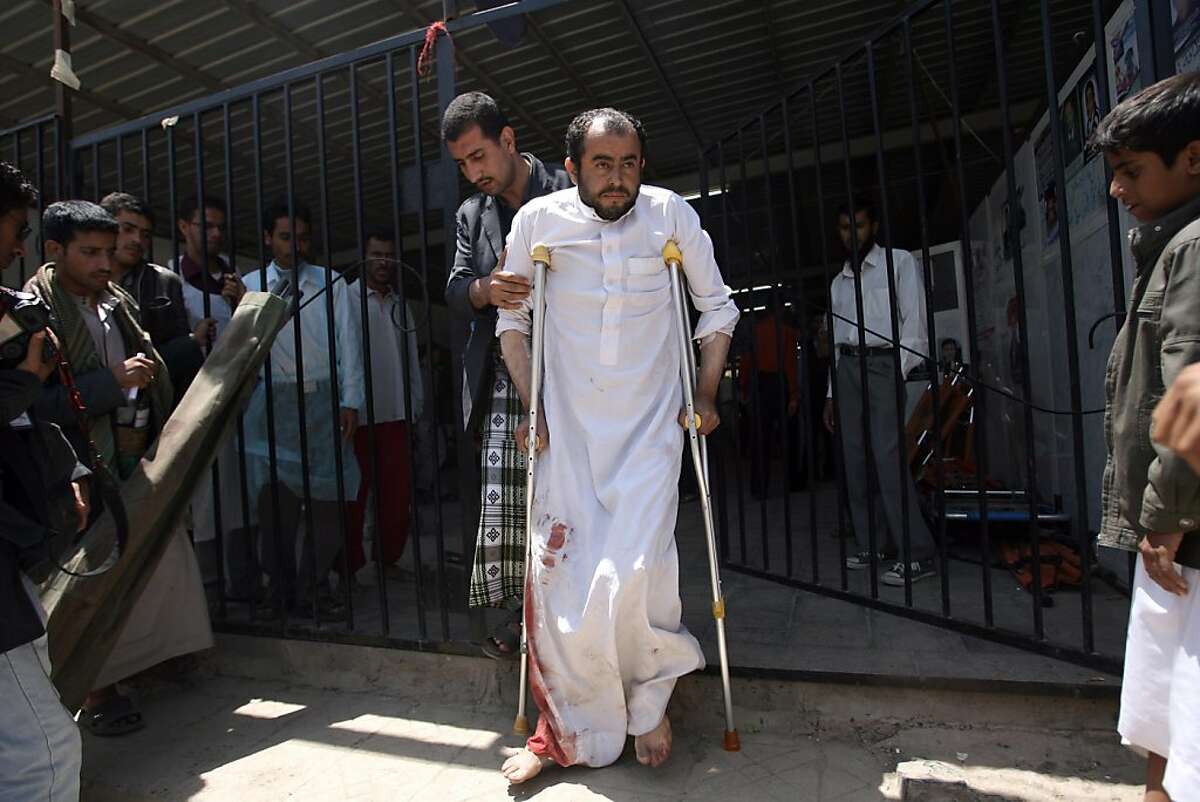 A wounded Yemeni anti-regime protester is helped by a comrade outside a hospital in Sanaa on September 24, 2011, as clashes rocked the Yemeni capital, leaving dozens of people dead a day after President Ali Abdullah Saleh returned from months of medical treatment in Riyadh carrying "the dove of peace." AFP PHOTO/ MOHAMMED HUWAIS (Photo credit should read MOHAMMED HUWAIS/AFP/Getty Images)