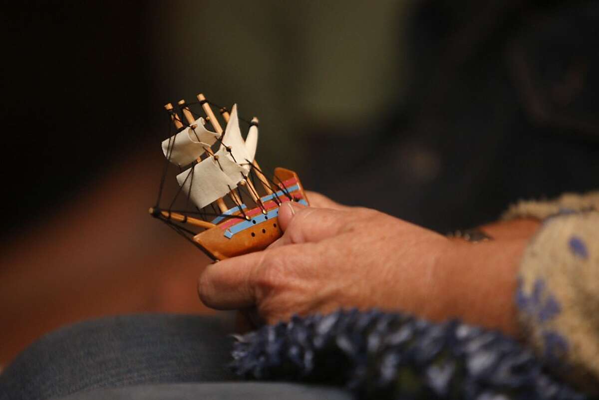 A woman holds a miniature sailing ship as she listens and sings with Chantey Sing, a choral group dedicated to singing traditional sea chanteys, at its monthly concert aboard the Balclutha sailing ship in San Francisco Calif., on September 3, 2011.
