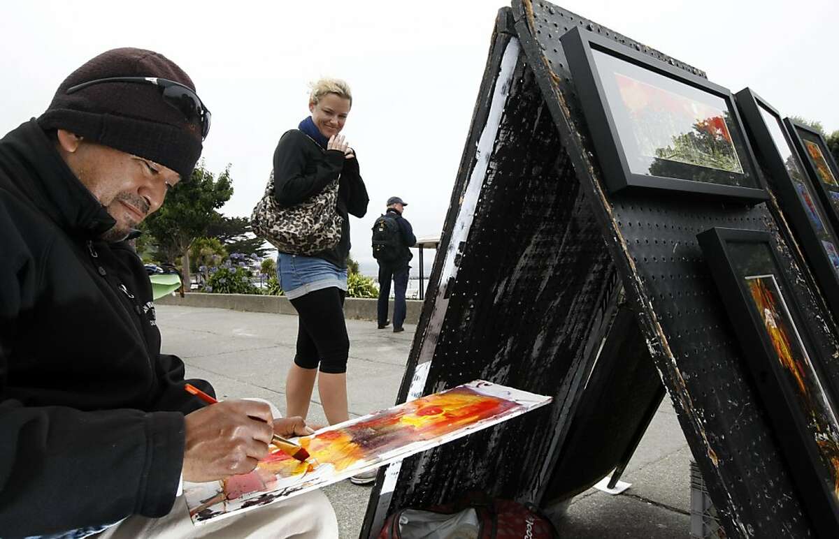 Hayley Stice a tourist from New Zealand looks over Eduardo Guzman, as he creates a painting at his sidewalk stand on Beach Street in San Francisco Fisherman's Wharf area between Hyde and Larkin streets Wednesday September 14, 2011.