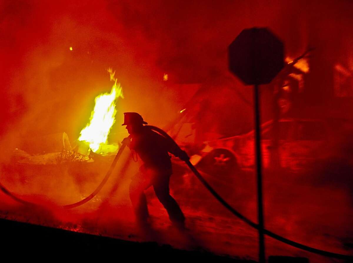 A firefighter helps battle the fire that was caused by an explosion from a gas line rupture.