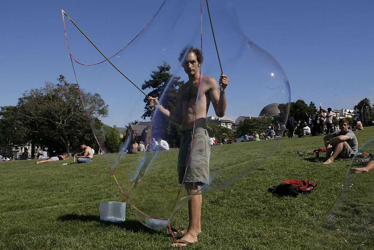 Using two tent poles, some long string, and a bucket of suds, Colin Bowring creates enormous bubbles that float above other people enjoying a beautiful sunny day at Dolores Park in San Francisco Calif., on August 26, 2011.