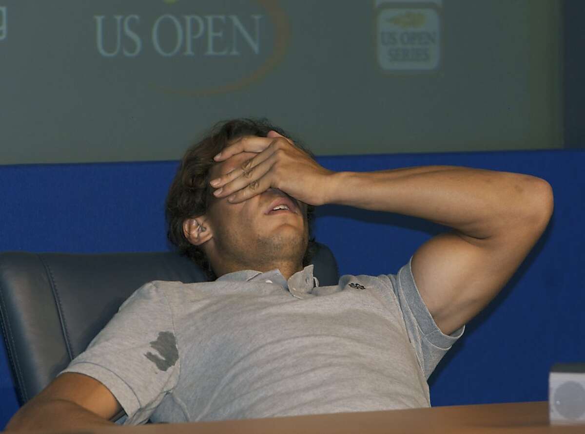 Rafael Nadal of Spain reacts to pain during a press conference after his match against David Nalbandian of Argentina during the U.S. Open tennis tournament in New York, Sunday, Sept. 4, 2011. Answering questions in Spanish, Nadal suddenly started grimacing in pain. He tilted his head back, covered his face with his arm. After a few nervous moments, Nadal popped back up. A simple leg cramp, he insisted. (AP Photo/Andrzej Kentla)