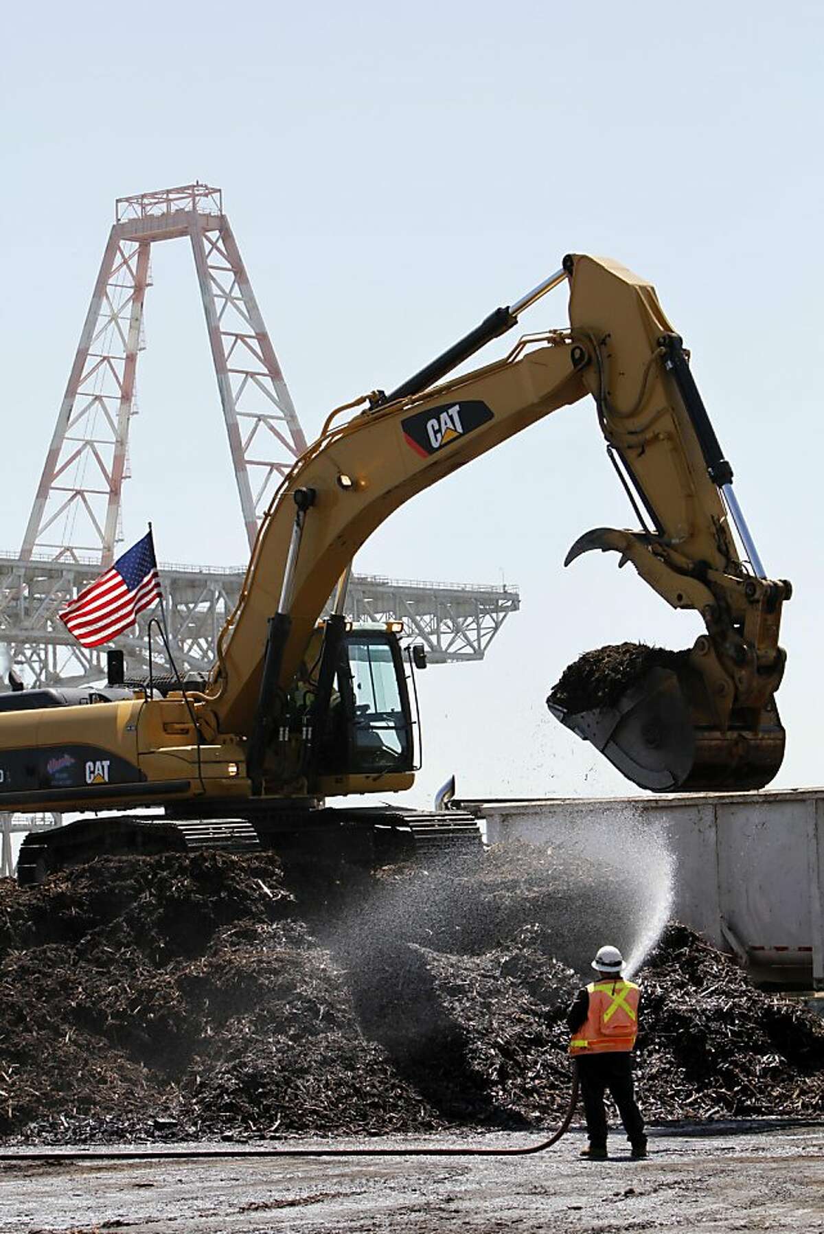 A worker sprays down piles of mulch created from dismantling old piers at Hunter's Point Naval Shipyard in San Francisco, Calif., Thursday, September 1, 2011. The Navy has been working with the EPA to clean up the toxic site.