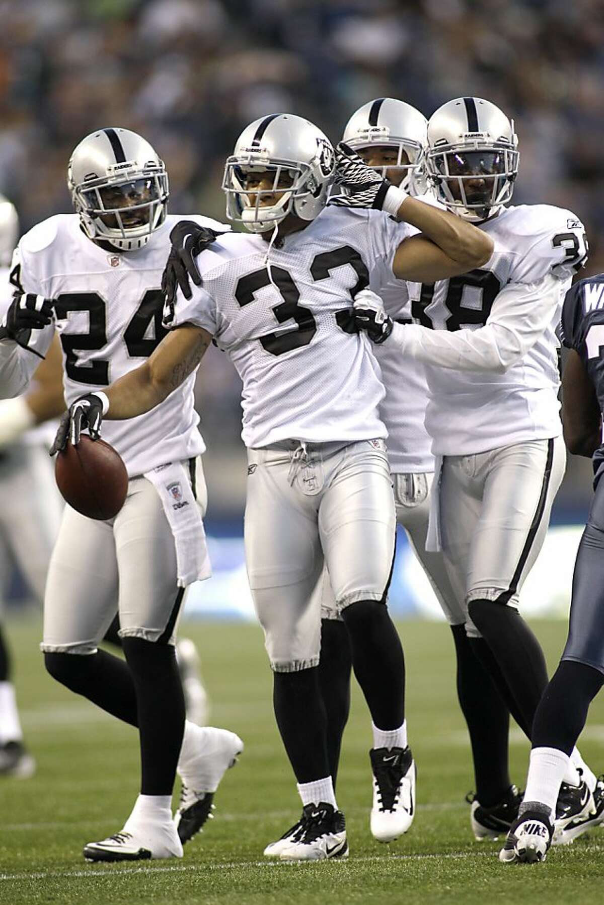 Oakland Raiders Tyvon Branch (33) in congratulated by his team after catching an interception against the Seattle Seahawks in the first half of a preseason NFL football game, Friday, Sept. 2, 2011, in Seattle. (AP Photo/Ted S. Warren)