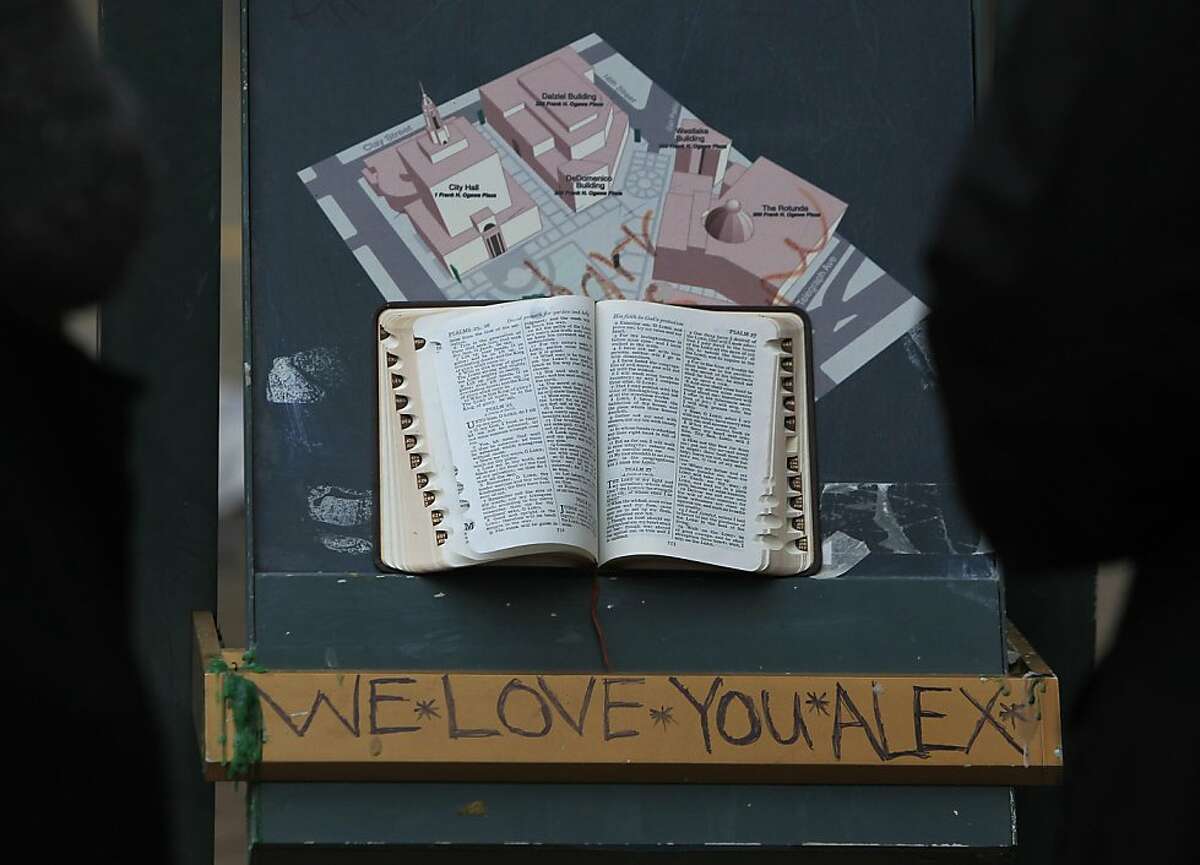 People stop to read a Holy Bible at a memorial for a young man, murdered at the site the night before, in front of the Occupy Oakland encampment in Oakland, Calif. on Friday, Nov. 11, 2011.