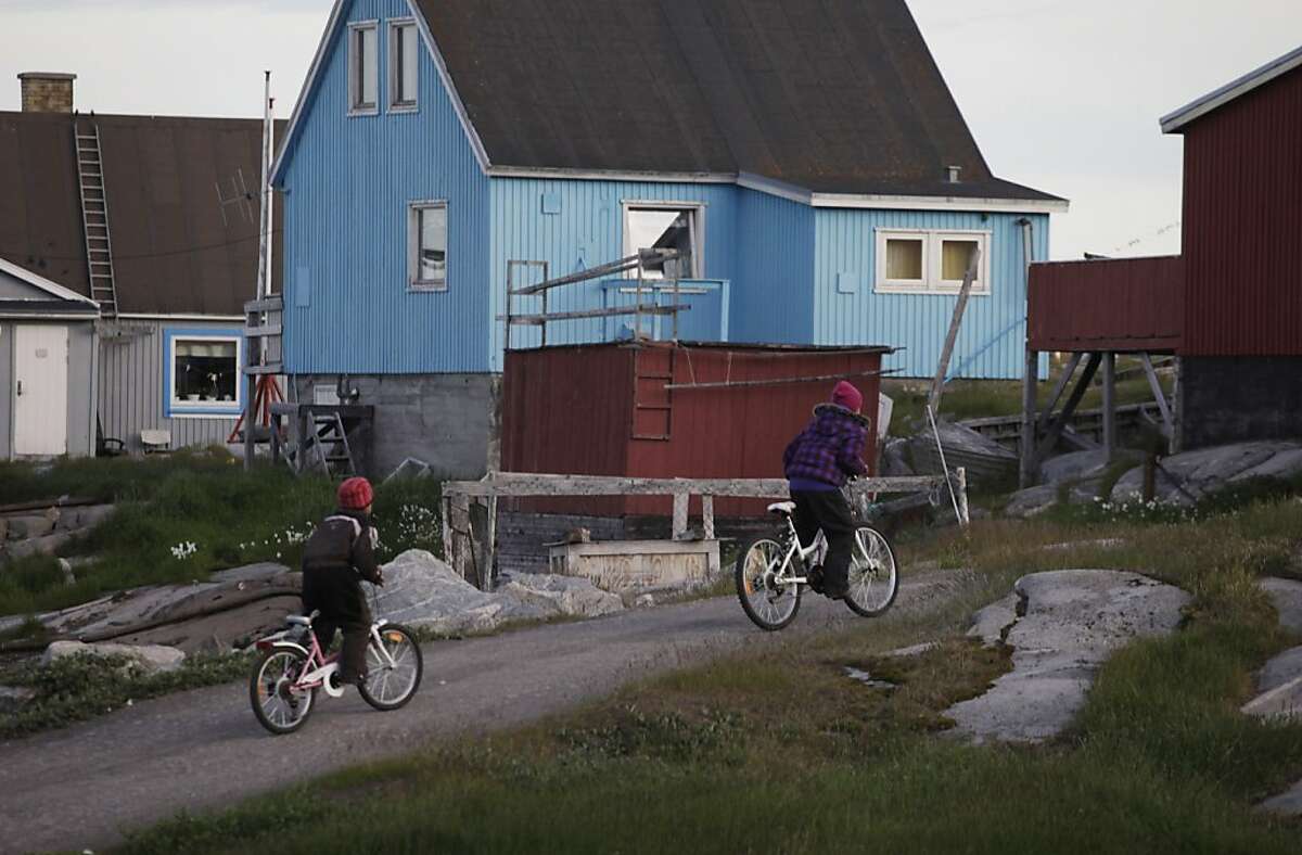 ADVANCE FOR USE SUNDAY, AUG. 21, 2011 AND THEREAFTER - In this July 21, 2011 photo, daughters of Greenlandic Inuit hunter Nukappi Brandt, Aaneeraq, 9, right, and Luusi, 8, ride their bicycles home late at night after an unsuccessful seal hunt with their father in Qeqertarsuaq, Disko Island, Greenland. Roughly 20 years ago, Brandt says, when winter sea ice became too thin to support dogsleds, seal hunting ceased to be a sustainable way of life here. (AP Photo/Brennan Linsley)