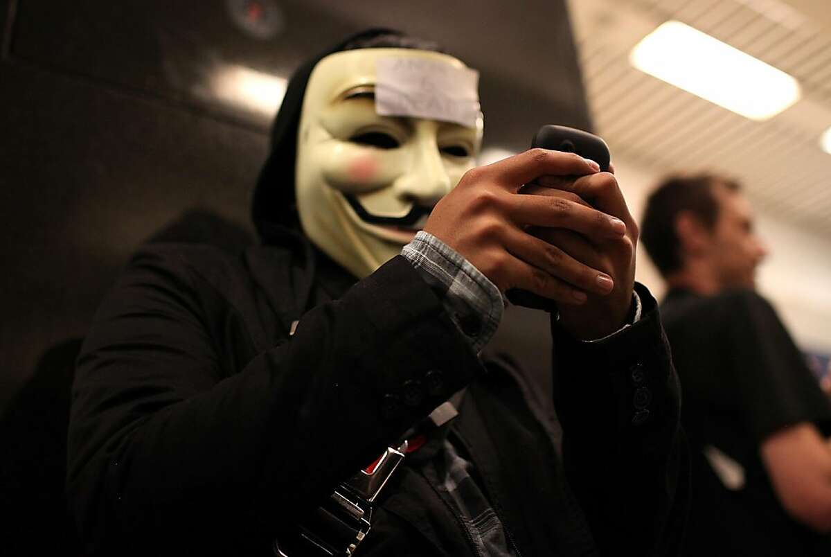 SAN FRANCISCO, CA - AUGUST 15: A demonstrator wears a mask as he tries to use his cell phone during a protest inside the Bay Area Rapid Transit (BART) Civic Center station on August 15, 2011 in San Francisco, California. The hacker group "Anonymous" staged a demonstration at a BART station this evening after BART officials turned off cell phne service in its stations last week during a disruptive protest following a fatal shooting of a man by BART police. (Photo by Justin Sullivan/Getty Images)