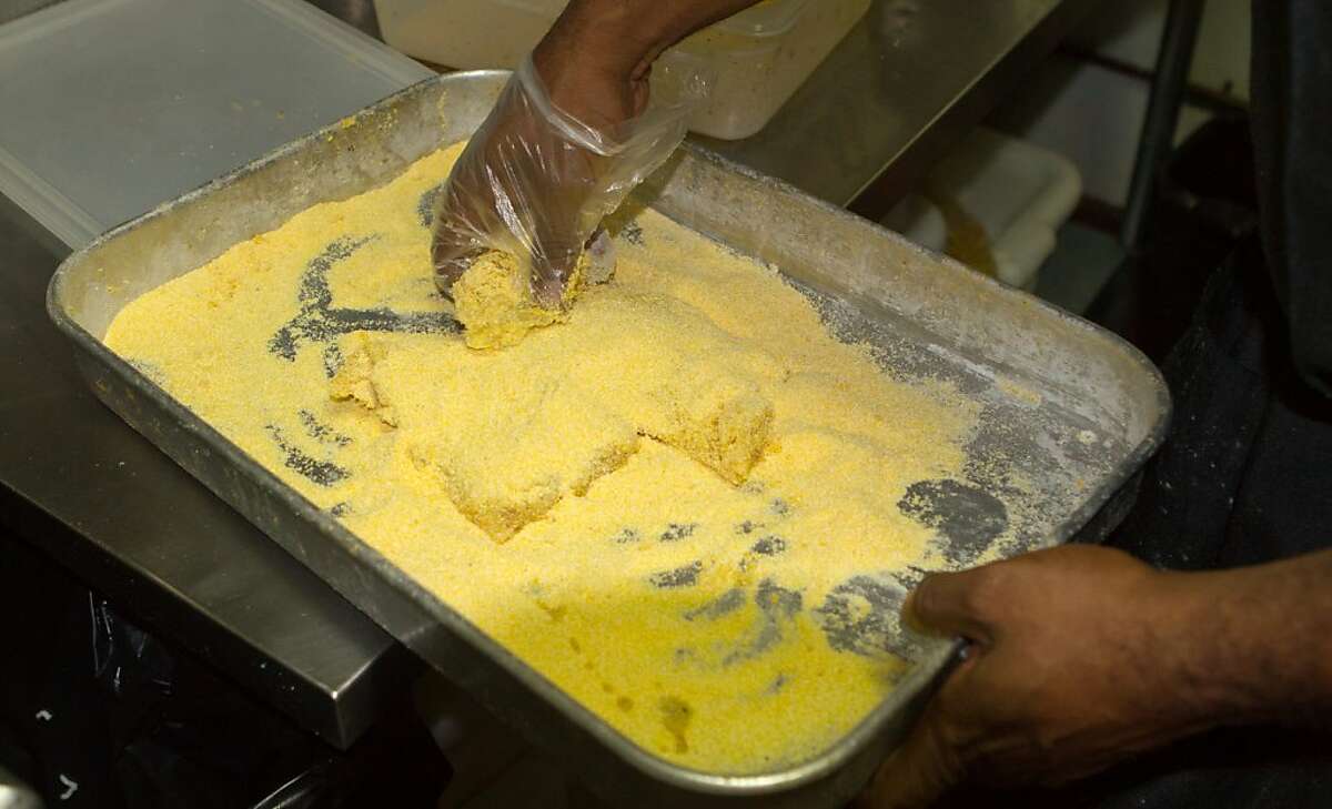 Chef Marcel Banks dips the catfish in corn meal before frying at Frisco Fried restaurant in San Francisco, Calif., on Monday August 29th, 2011.