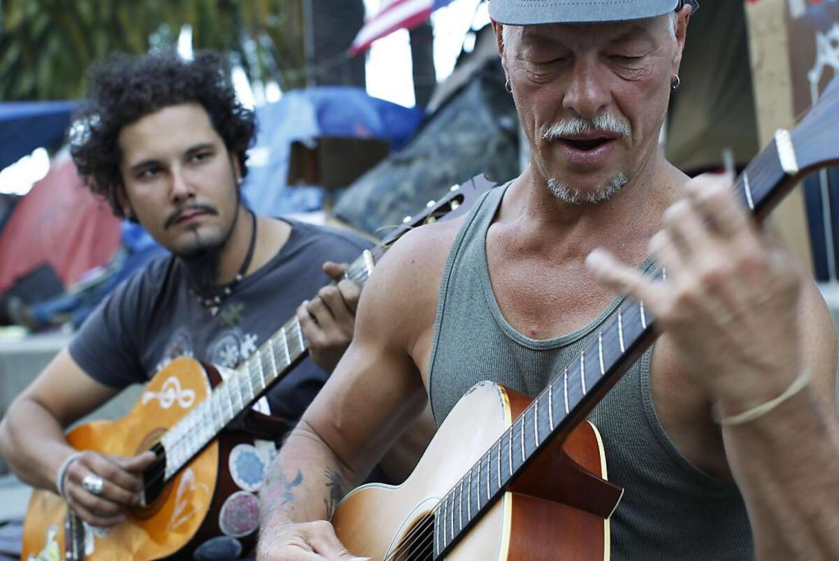 Occupy San Francisco participant Erik Anderson, of Connecticut and Mingalo Mars, of San Francisco makes music with their guitars at the Occupy San Francisco's camping groung at Justin Herman Plaza in San Francisco, Calif. Friday, October 28, 2011.