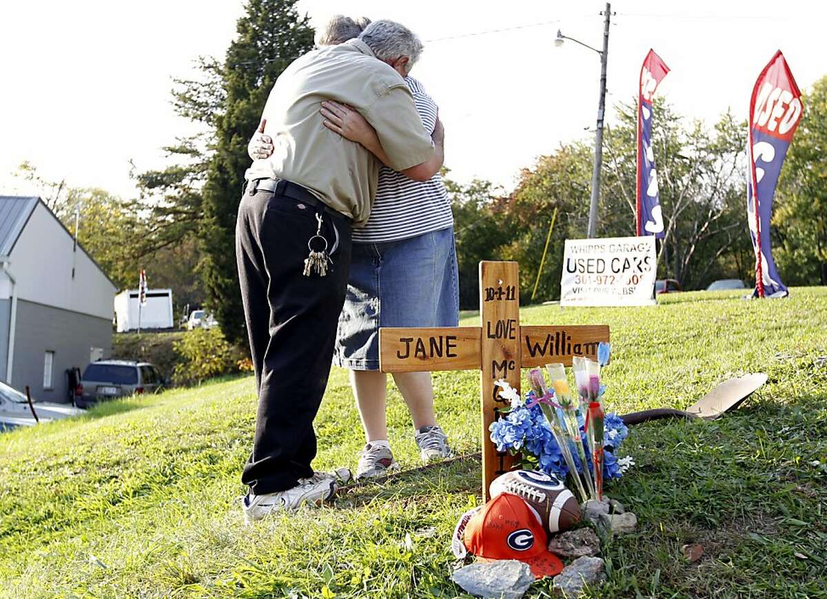 Charlene and Charles Barnes embrace each other after planting a cross an flowers with the names of Jane and William McQuain at the side of the road in Clarksburg, Md. Tuesday Oct. 18, 2011, where Maryland police found remains Tuesday that they believe are those of the missing boy whose mother was discovered slain. (AP Photo/Jose Luis Magana)