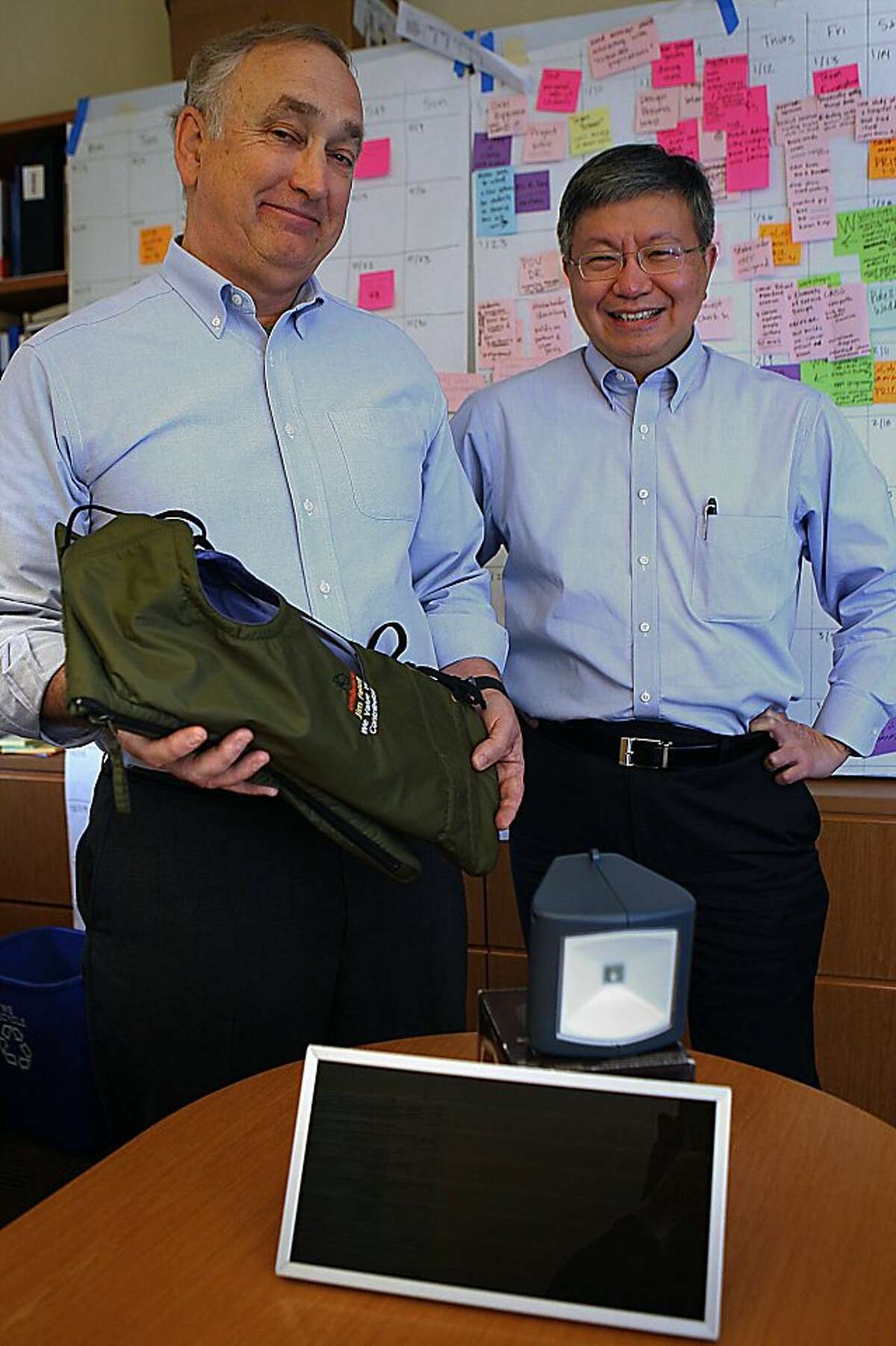 Faculty co-directors of the new institute James Patell (left) and Hau Lee (right) with two of their students ideas at the Knight Management Center on Stanford University in Palo Alto, Calif., on Thursday, November 3, 2011. Patell is carrying a baby warmer designed by alumni Jane Chen to be used as an incubator in impoverished countries, and in front is an early prototype of the d.light from alumni Sam Goldman and Ned Tozum to light villages using solar.