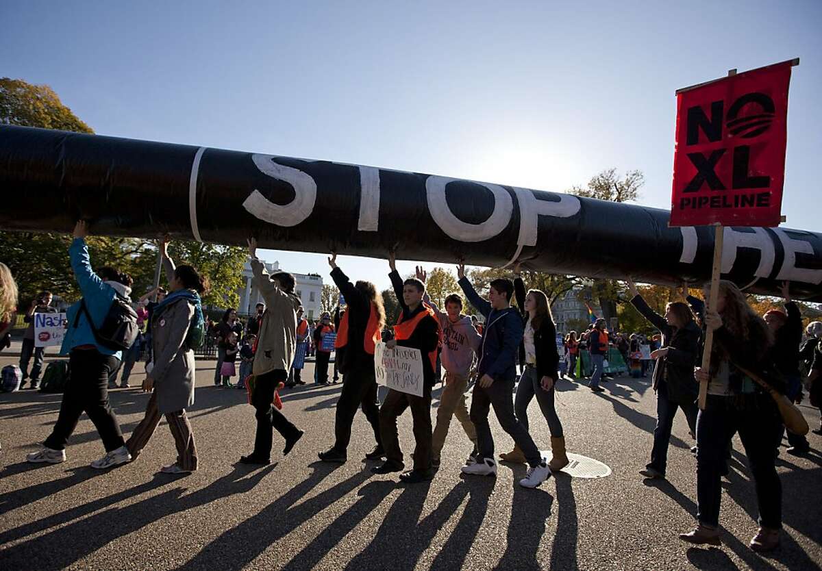 Demonstrators march with a replica of a pipeline during a protest against the Keystone XL Pipeline outside the White House on Sunday, Nov. 6, 2011, in Washington. (AP Photo/Evan Vucci)