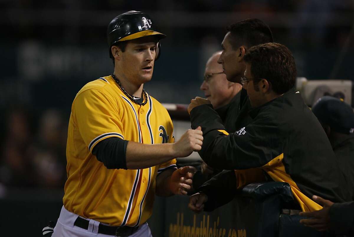Oakland player Josh Willingham is congratulated by his team after scoring the first run of the night for the Oakland Athletics during the Oakland game against the Texas Rangers in Oakland Calif., on August 11, 2011.