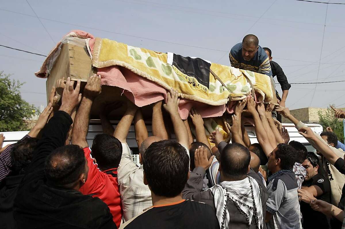Friends and relatives load the coffin of a man killed in a bomb attack at a music store in Baghdad, Iraq, Friday, Oct. 28, 2011. On Thursday twin bombing killed and wounded scores of people in a Shiite neighborhood in Baghdad the deadliest attack to rock Iraq since President Barack Obama declared the full withdrawal of U.S. forces at the end of the year. (AP Photo/Karim Kadim) Ran on: 10-29-2011 Friends and relatives load the coffin of a man killed in a bomb attack at a music store in Baghdad.