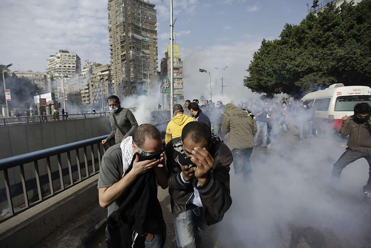 Egyptian anti-government activists run for a cover from the tear gaz during clashes with the riot- police in Cairo, Egypt, Friday, Jan. 28, 2011. Egyptian activists protested for a fourth day as social networking sites called for a mass rally in the capital Cairo after Friday prayers, keeping up the momentum of the country's largest anti-government protests in years. (AP Photo/Ben Curtis) Ran on: 01-29-2011 Anti-government activists run for cover from tear gas during clashes with riot police in Cairo Friday. Battling police with stones and firebombs, protesters burned down the ruling party headquarters and defied a nighttime curfew. A3 In Business, high-tech leaders respond to the governments Internet shutdown. D1 Ran on: 01-29-2011 Anti-government activists run for cover from tear gas during clashes with riot police in Cairo Friday. Battling police with stones and firebombs, protesters burned down the ruling party headquarters and defied a nighttime curfew. A4 In Business, high-tech leaders respond to the governments Internet shutdown. D1
