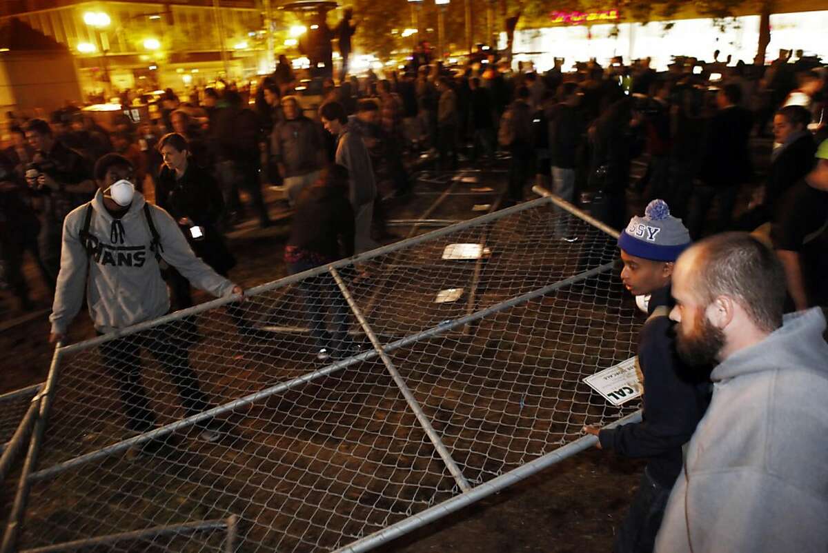 An Occupy Oakland protester removes a section of chain link fence from where the group's camp had previously been located. Occupy Oakland protesters returned to Frank Ogawa Plaza in Oakland, Calif, on Wednesday, October 26, 2011. .