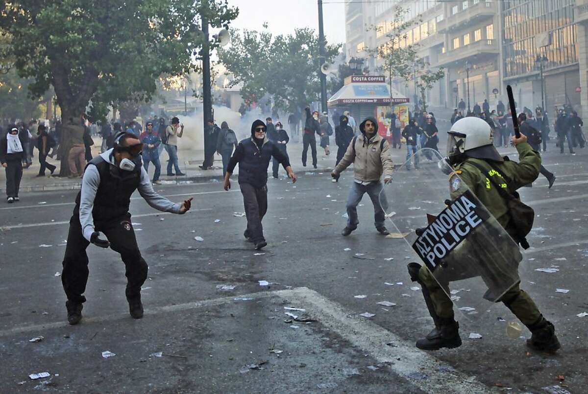 Protesters challenge a Greek riot police officer, during clashes in central Athens, Wednesday, Oct. 19, 2011. Greek anger over new austerity measures and layoffs erupted into violence Wednesday, as demonstrators hurled chunks of marble and gasoline bombs and riot police responded with tear gas and stun grenades that echoed across Athens' main square. (AP Photo/Lefteris Pitarakis)