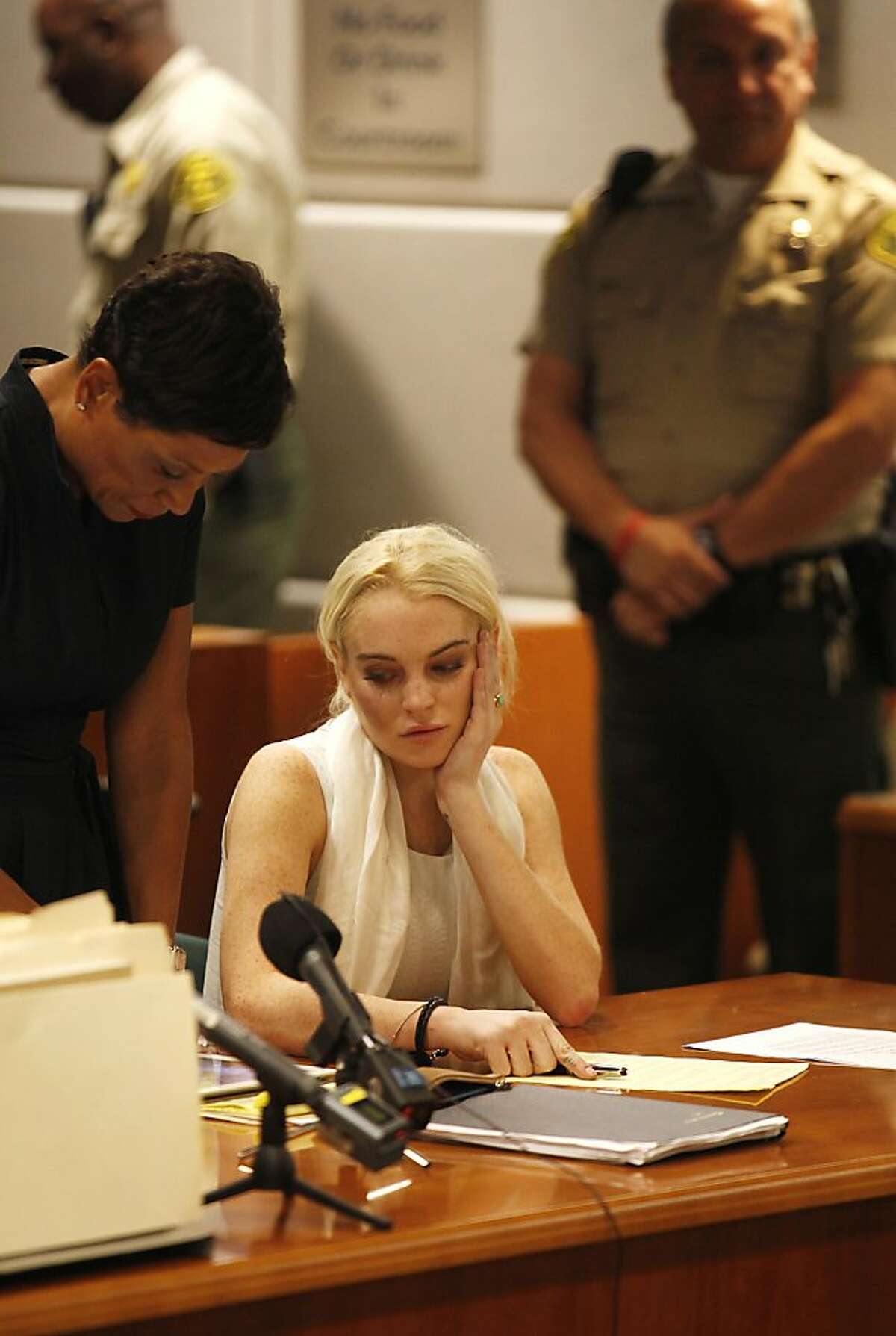 Actress Lindsay Lohan listens at her progress hearing at the Airport Branch Courthouse in Los Angeles October 19, 2011. At left is Lohan's attorney Shawn Chapman Holley. Lohan was handcuffed and taken into custody with bail set at USD $100,000 in the case of a misdemeanor count of theft involving a necklace taken from a jewelry store. AFP PHOTO / POOL / Mark Boster (Photo credit should read Mark Boster/AFP/Getty Images)