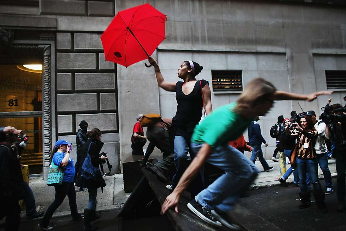 NEW YORK, NY - OCTOBER 14: Demonstrators associated with the 'Occupy Wall Street' jump over barricades as they face off with police in the streets of the financial district after the deadline for their removal from Zuccotti park was postponed on October 14, 2011 in New York City. Many of the 'Occupy Wall Street' demonstrators have been living in Zuccotti Park in the Financial District near Wall Street. The activists have been gradually converging on the financial district over the past three weeks to rally against the influence of corporate money in politics among a host of other issues. The protests have begun to attract the attention of major unions and religious groups as the movement continues to grow in influence. Dozens of protesters were arrested in the morning demonstrations. (Photo by Spencer Platt/Getty Images)