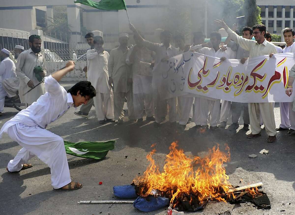 A Pakistani protester beats a burning effigy of U. S. Adm. Mike Mullen, during an anti-American rally in Peshawar, Pakistan, on Tuesday, Oct, 4, 2011. U.S. pressure on Pakistan to attack Afghan militants on its soil will not succeed, the Pakistani prime minister told a gathering of political and military leaders. Banner reads "Down with America rally." (AP Photo/Mohammad Sajjad)