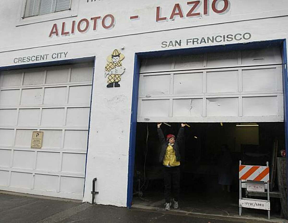 Annette Traverso opens a roll-up door for one of the last times at her family's Alioto-Lazio Fish Company in San Francisco, Calif., on Thursday, Jan. 13, 2011. The family has decided to shut down the business indefinitely until an extensive oil clean-up project by the Port and Exxon is completed directly behind their building.